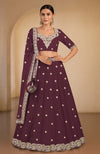 A woman models a maroon lehenga set with intricate silver embroidery.