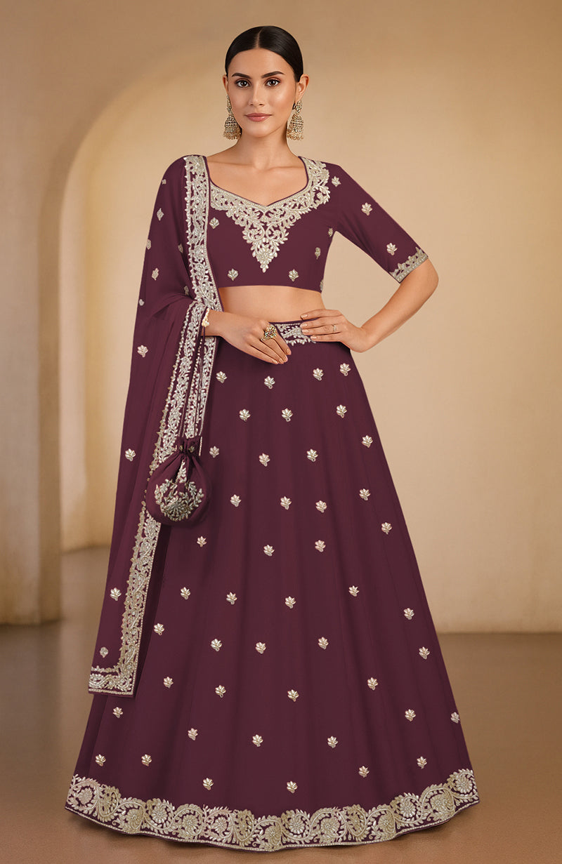 A woman models a maroon lehenga set with intricate silver embroidery.