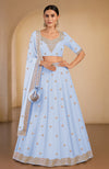 A light blue lehenga set with intricate gold embroidery and a matching dupatta.