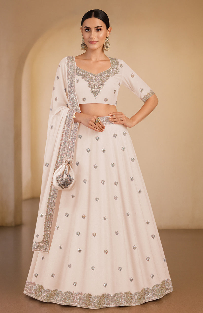 A woman models a sea salt lehenga set with intricate embroidery and a matching dupatta.